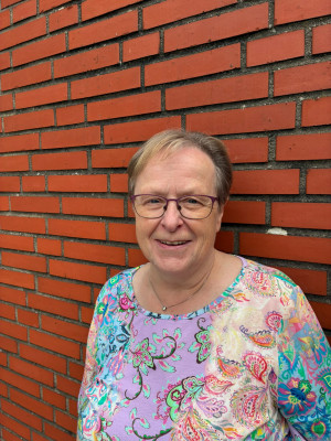 Prädikantin Helga Schröder vor einer roten Ziegelmauer.