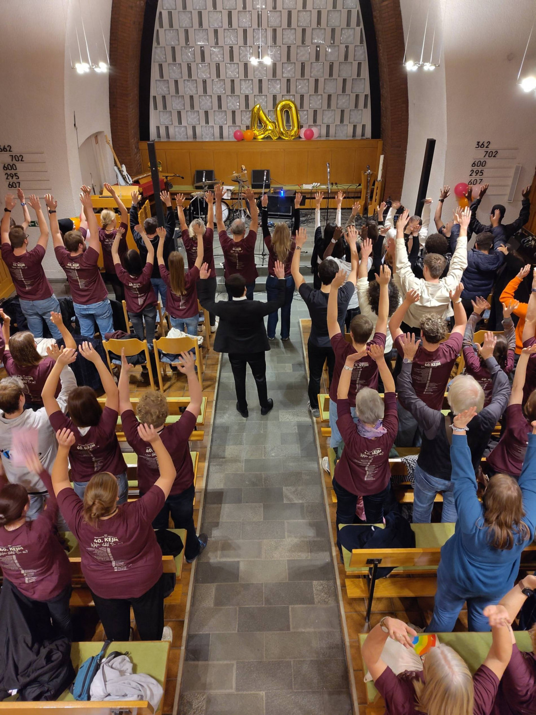 Viele Jugendliche und junge Erwachsene stehen in der Christuskirche in Moers-Scherpenberg und jubeln mit Händen in der Höhe den beiden Luftballons entgegen, die eine 40 bilden.