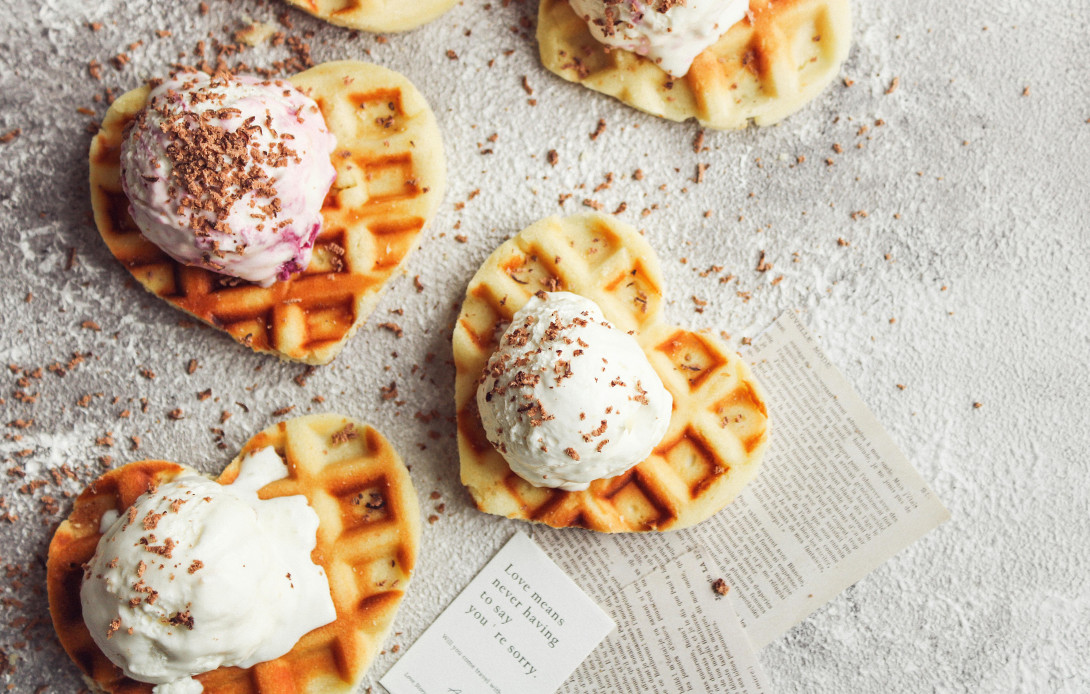 Selbstgebackene Waffeln in Herzform mit Vanilleeis und Streuseln oben auf.